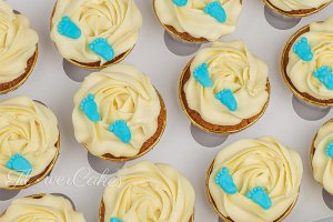 Cupcakes till en babyshower, med små babyfötter av sockerpasta på toppen.