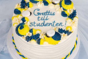 Studenttårta dekorerad i Sverigetema med några ätbara studentmössor på toppen.