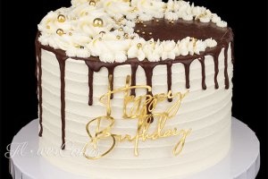 Födelsedagstårta dekorerad med spritsning, guldfärgat strössel, chokladdrip och en guldfärgad caketopper på framsidan.