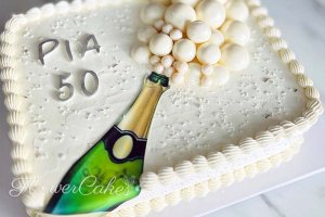 Fyrkantig tårta dekorerad med en champagneflaska som sprutar bubblor.