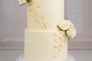 Förlovningstårta med mönster, guld och levande blommor.