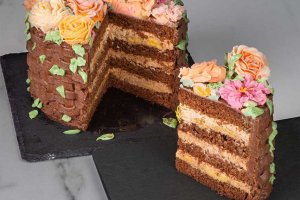 Chokladtårta i form av en korg, dekorerad med spritsade blommor - skuren så att man ser de olika lagren inuti.